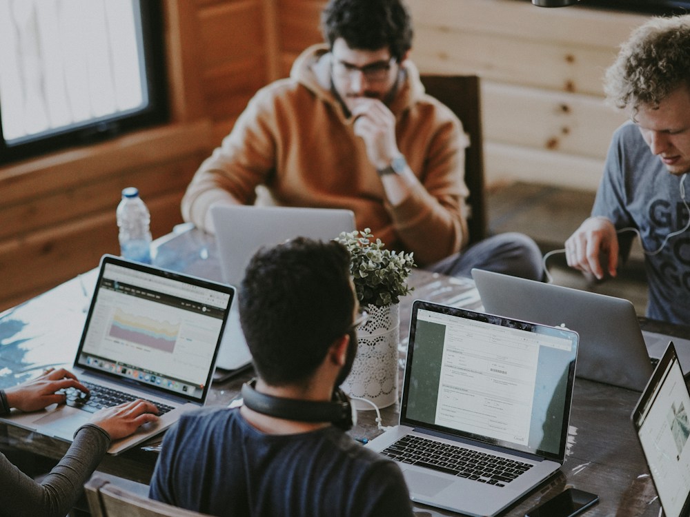 Profissionais colaborando em uma mesa de trabalho com computadores